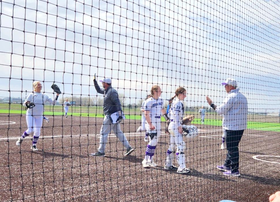 Senior Avry Trotter goes to give Assistant Coach Jason Anderson a high five while Head Coach T.C. Weinandt talks to pitcher Emma Barnett and catcher Mia Riibe after a great inning of 3 outs and no runs versus West Central on April 22. Photo by Kelly Riibe • times2reporter@gmail.com