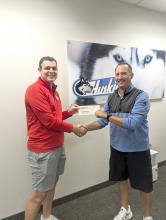 Former EPJ student Hunter Goehring hands a donation from The Scheels Give Back Program to EPJ Boys Golf Head Coach Kelly Haberling. Submitted photo