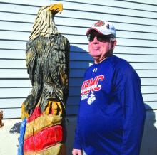Tom Jacobs stands next to a carved eagle statue at his home in McCook Lake. It was carved by his friend Mike Caskey. Photo by Kelly Riibe • times2reporter@gmail.com