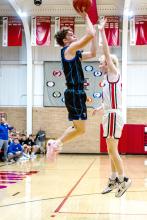 Carson Timmins shows his athletic ability as he jumps clear above his Vermillion defender on Jan. 16 in Vermillion. Photo by Peterman Sports Photography stevepeterman5@gmail.com