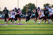 Senior Jackson Boonstra runs through a big hole under the “Friday Night Lights” at DV. Photos by Peterman Sports Photography • stevepeterman5@gmail.com