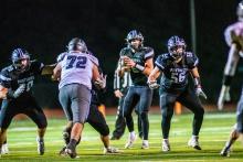 Drew Lukken looks for a receiver while Cooper Bernard (#70) and Jace Hutchinson (#56) provide protection versus SFC. Photo by Peterman Sports Photography • stevepeterman5@gmail.com