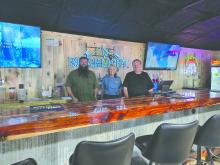 From left: Brian Irwin, Traci McDonald, and Brian Oedekoven gather behind the handcrafted bar top—built with local pride and hometown materials. Photos by Shannon Jost • timesleader1@gmail.com