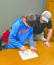 Lucas McMahan, a student at EPJ, shows Elk Point’s chief of police how to use the communication cards that the Huskies delivered on April 15, 2026. From left: Lucas McMahan and Police Chief Jacob Limoges.