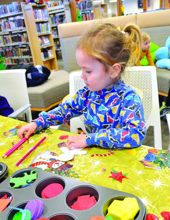 Santa Claus read a story to children at the North Sioux City library Dec. 15. (Bottom) Ferne Roberts, of North Sioux City, decorate a gingerbread man ornament at an arts and crafts station. Photos by Kelly Riibe • times2reporter@gmail.com