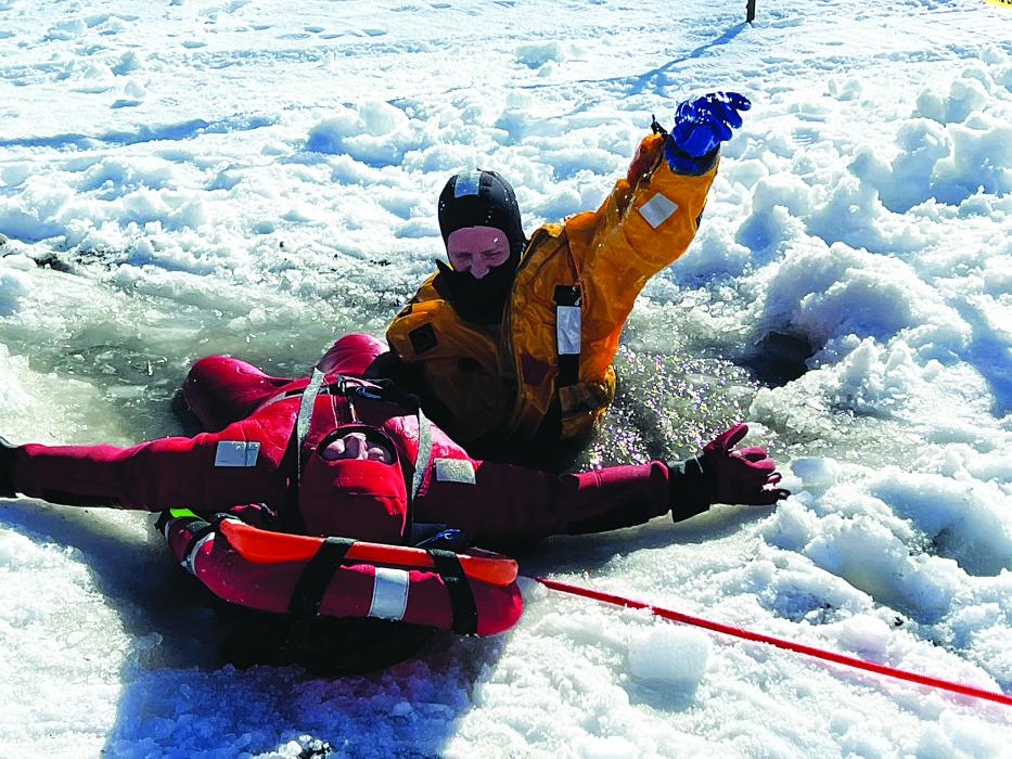 Viktor Sundleaf (in yellow) signals to his fellow firefighters that the victim, Jason Bame (in red) is secure and ready to be pulled out of the hole in the ice. Photo courtesy of Kevin Carl