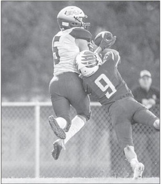 Devon Schmitz takes to the air and completes the pass despite the defensive coverage. Photo by Peterman Sports Photography photoman@iw.net