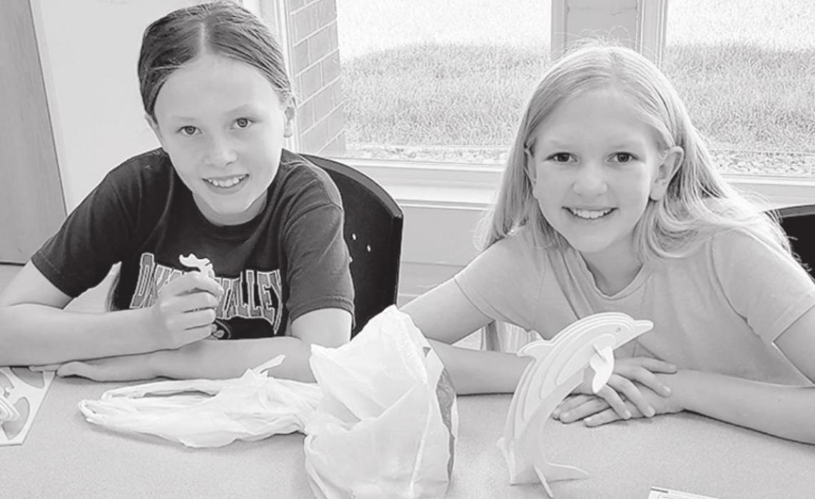 Marlee Olsen, left, holds up a piece of her 3-D shark and Katie Jo Hale shows her finished product of a constructed dolphin.